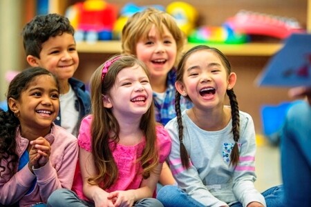 five early learning students laughing in a classroom